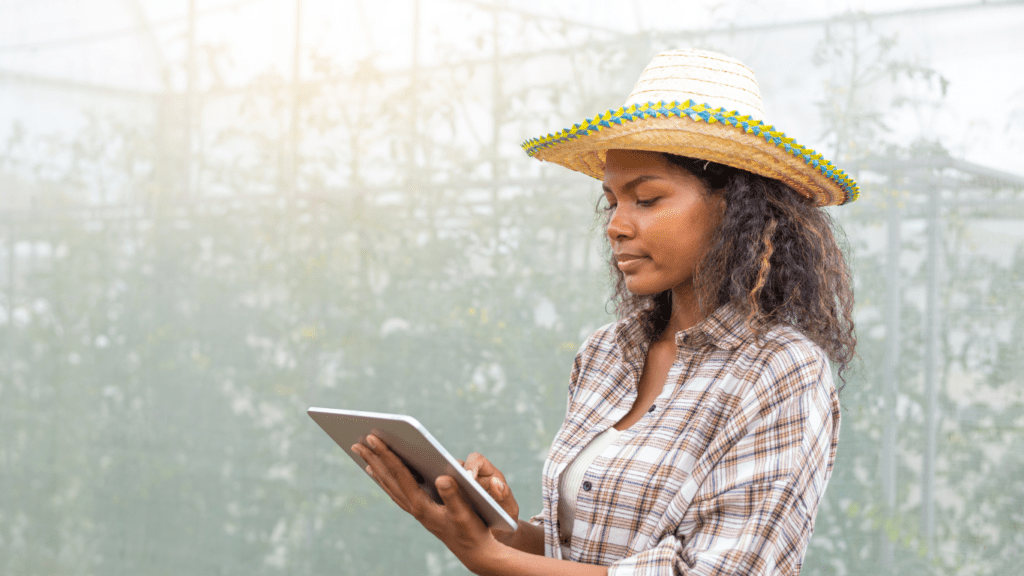 A person standing in a greenhouse holding an x-ray image of a tomato plant