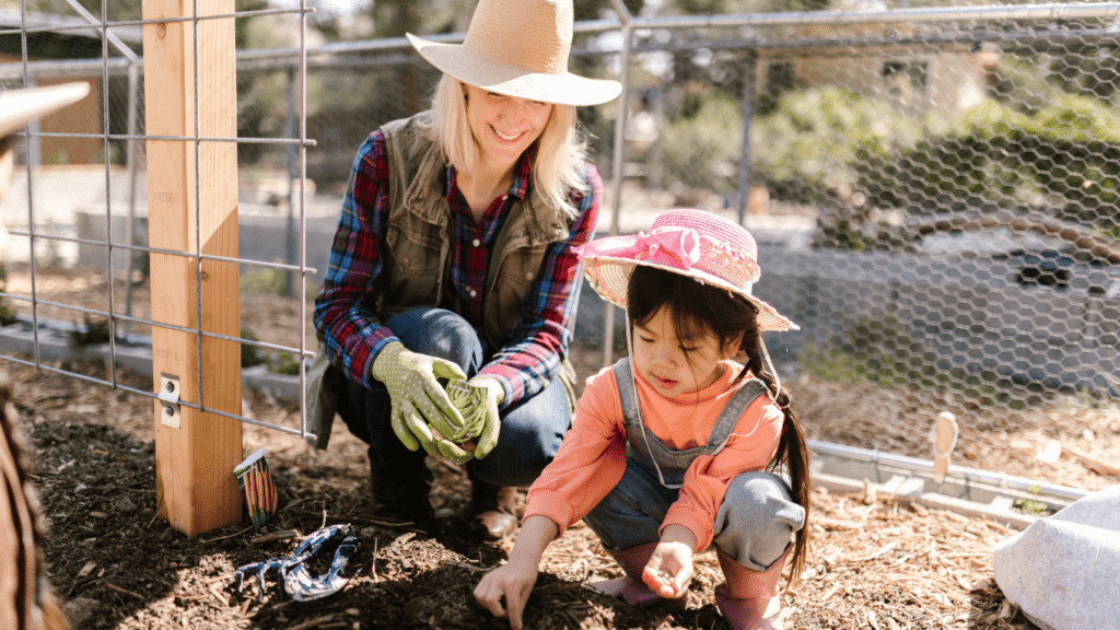 A person and a child are planting seeds in a garden