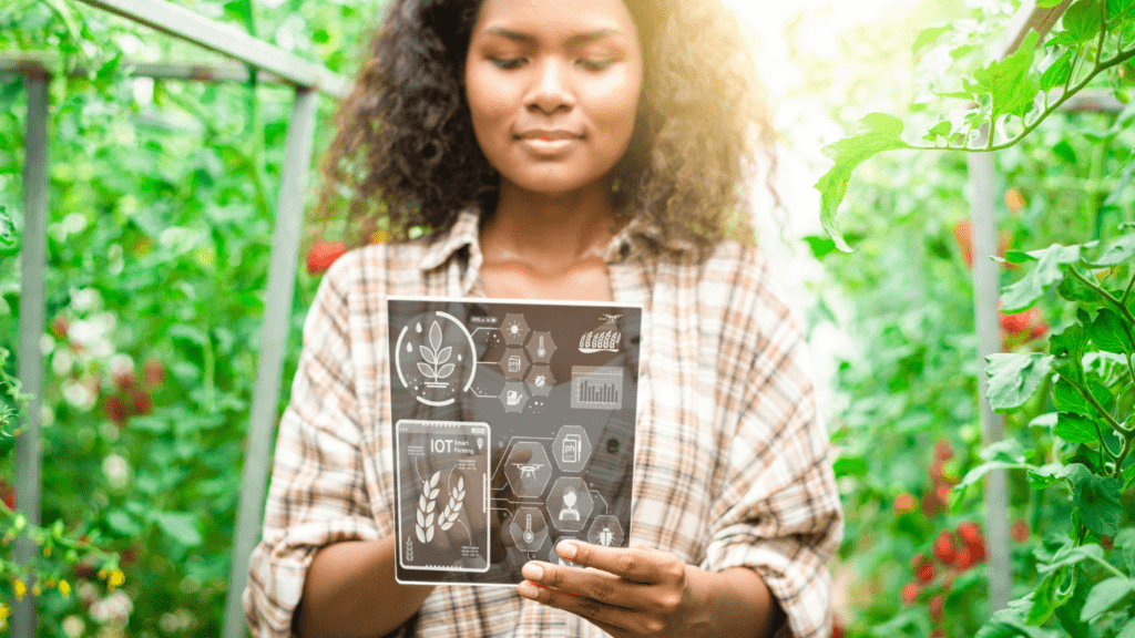 A person standing in a greenhouse holding an x-ray image of a tomato plant