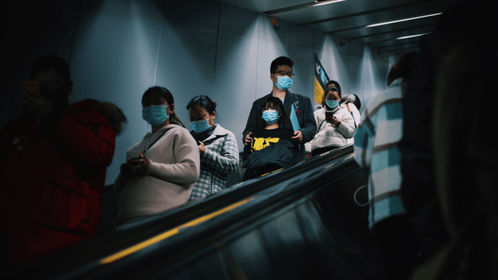 people wearing face masks walk through a subway station